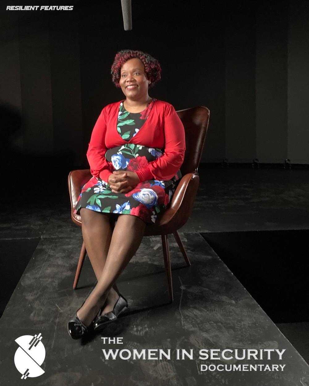 A woman seated alone in the leather interview chair on the darkened set, facing camera.